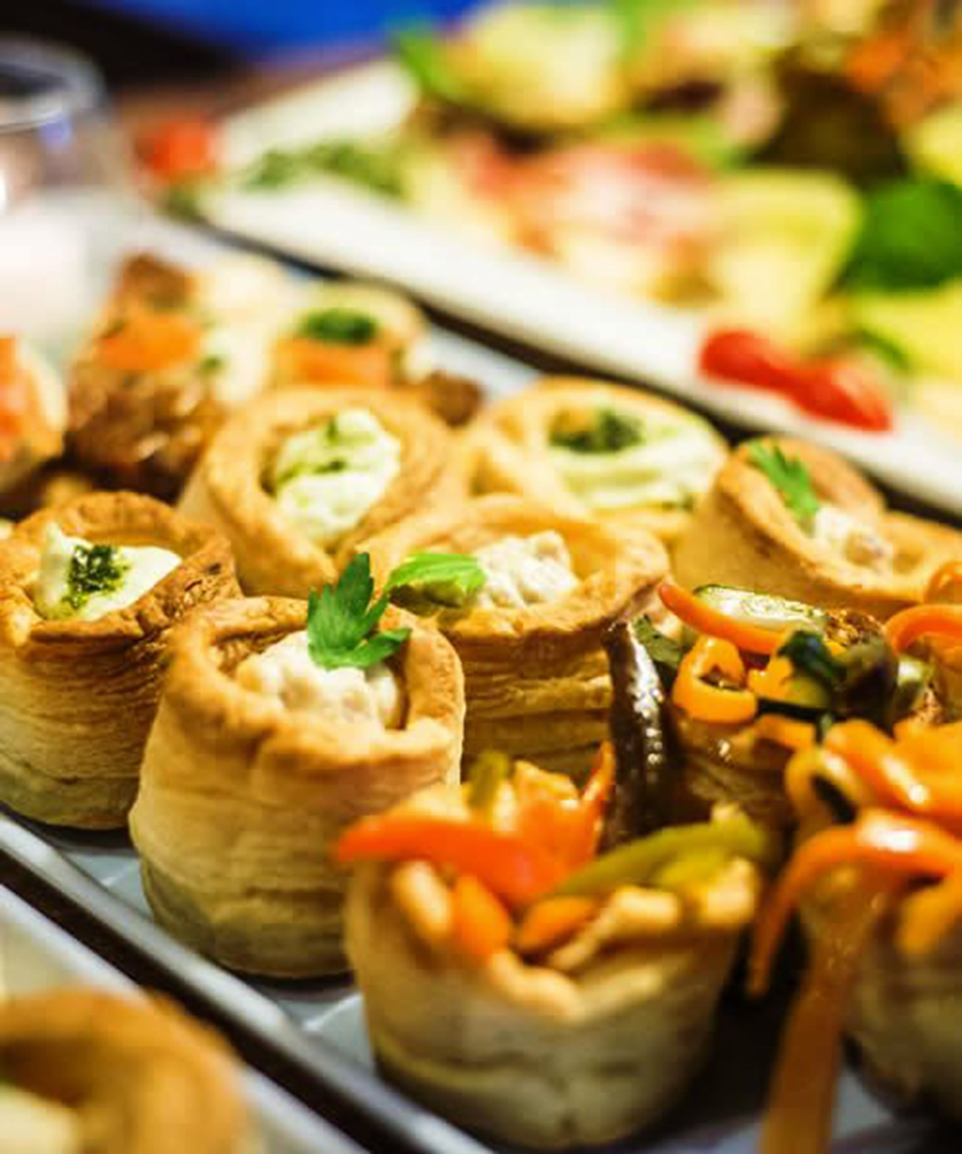 Een buffet met diverse gerechten, waaronder gebakjes van bladerdeeg en een selectie groenten.