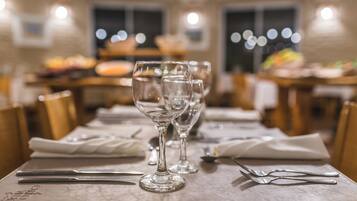 Una mesa de comedor dispuesta con copas de vino, cubiertos y una servilleta.
