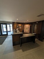 Una recepción con un ordenador, un mapa en la pared y vistas al exterior a través de puertas de cristal.