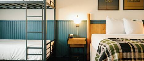 A bunk bed room with a desk and a lamp.