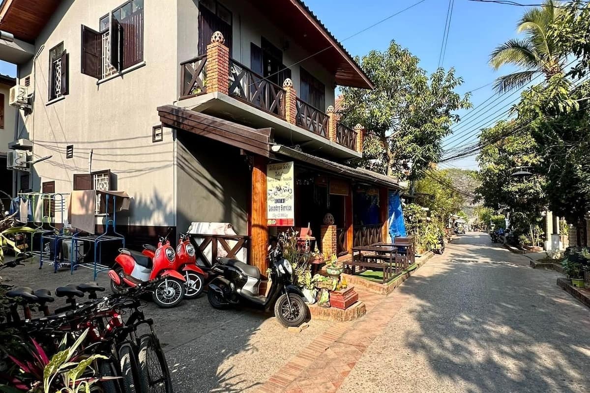 A two-story building with a balcony, a signboard, and a parked scooter.