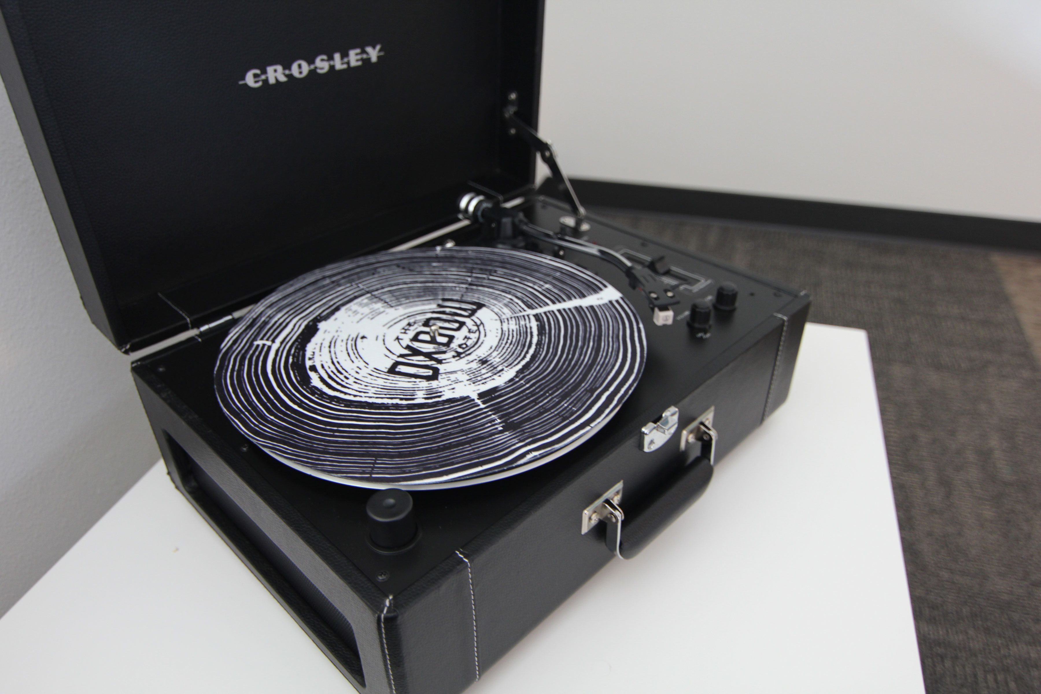 Un tocadiscos Crosley con un disco de vinilo sobre una superficie blanca.