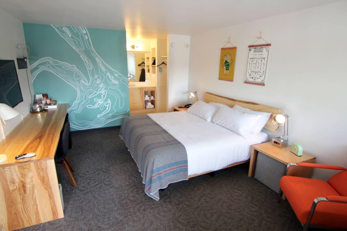 Habitación de hotel con cama, escritorio, silla, armario y baño.
