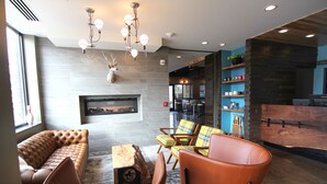 Eine moderne Lobby mit Ledersitzgelegenheiten, einem Kamin und einer Bar.