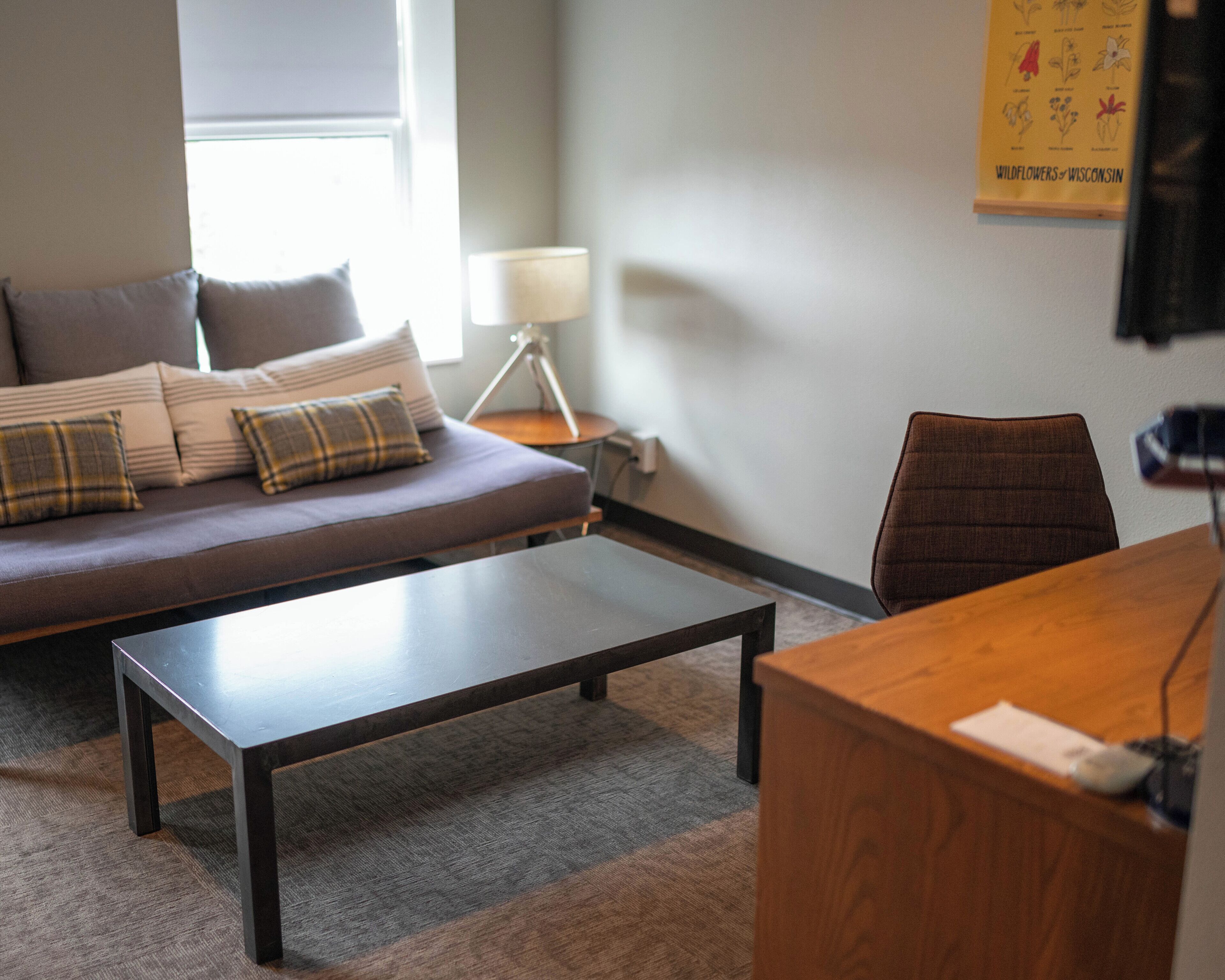 Un salon moderne comprenant un canapé, une table basse, un bureau et une lampe.