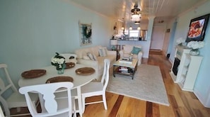 A spacious living room with a dining area, a kitchen in the background, and a fireplace.