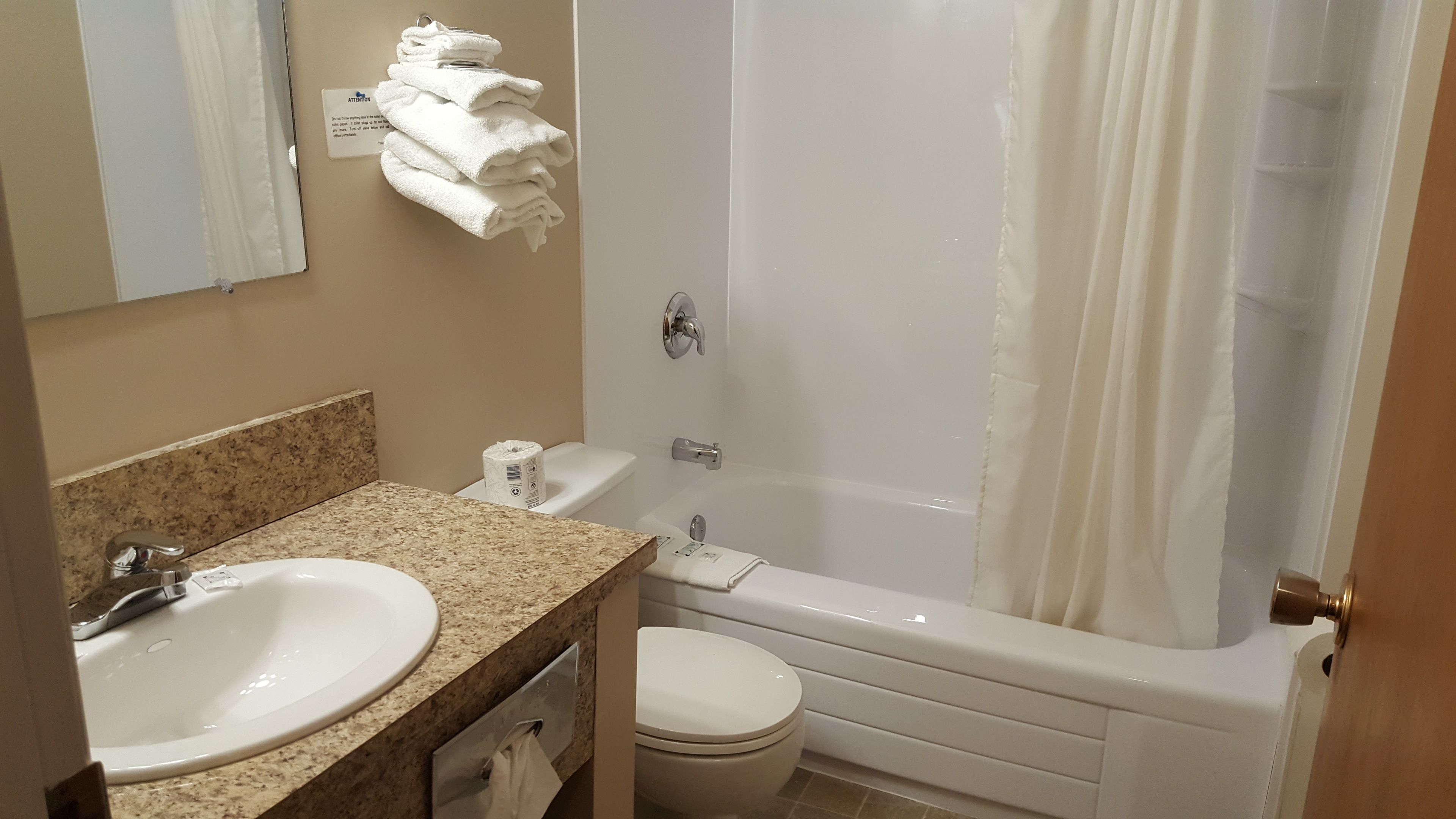 A bathroom with a sink, toilet, and bathtub. There are towels hanging on the wall.