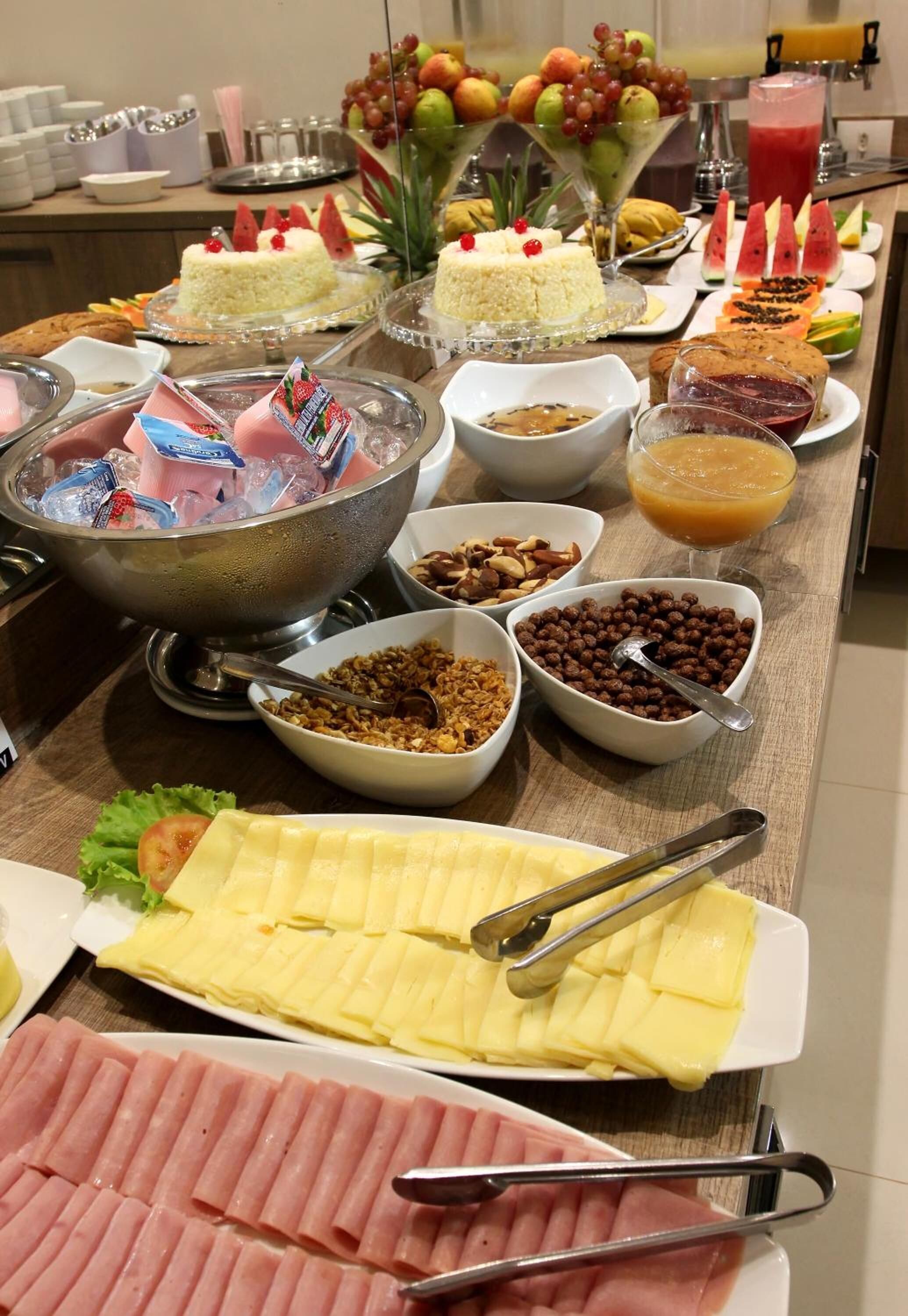 A buffet with various food items including cakes, fruits, and a hot beverage station.