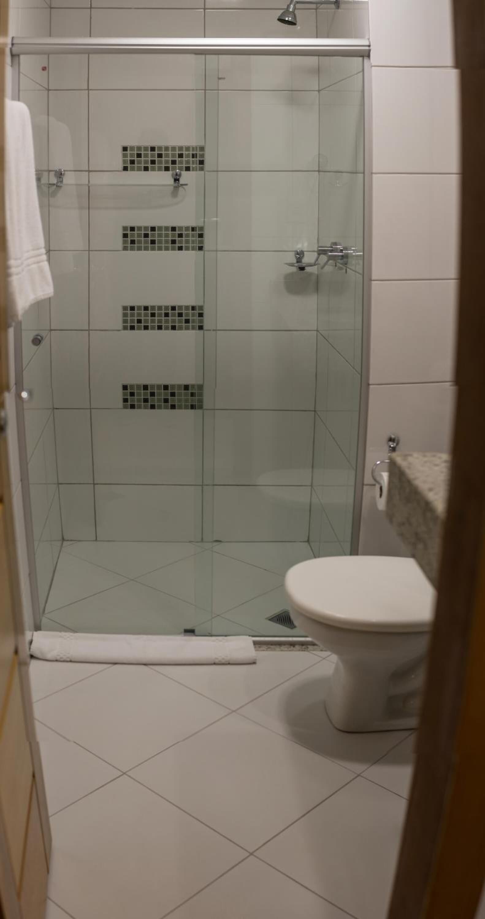 Eine Duschkabine aus Glas, eine weiße Toilette und ein gefliester Boden.
