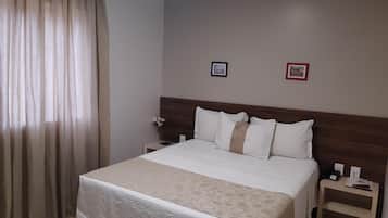 A hotel room with a large bed, a wooden headboard, two bedside tables, and a nightstand.