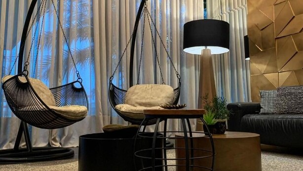 A modern living room with two hanging chairs, a floor lamp, a round coffee table, and a sofa. - L'Acordes Hotel (Porto Velho)