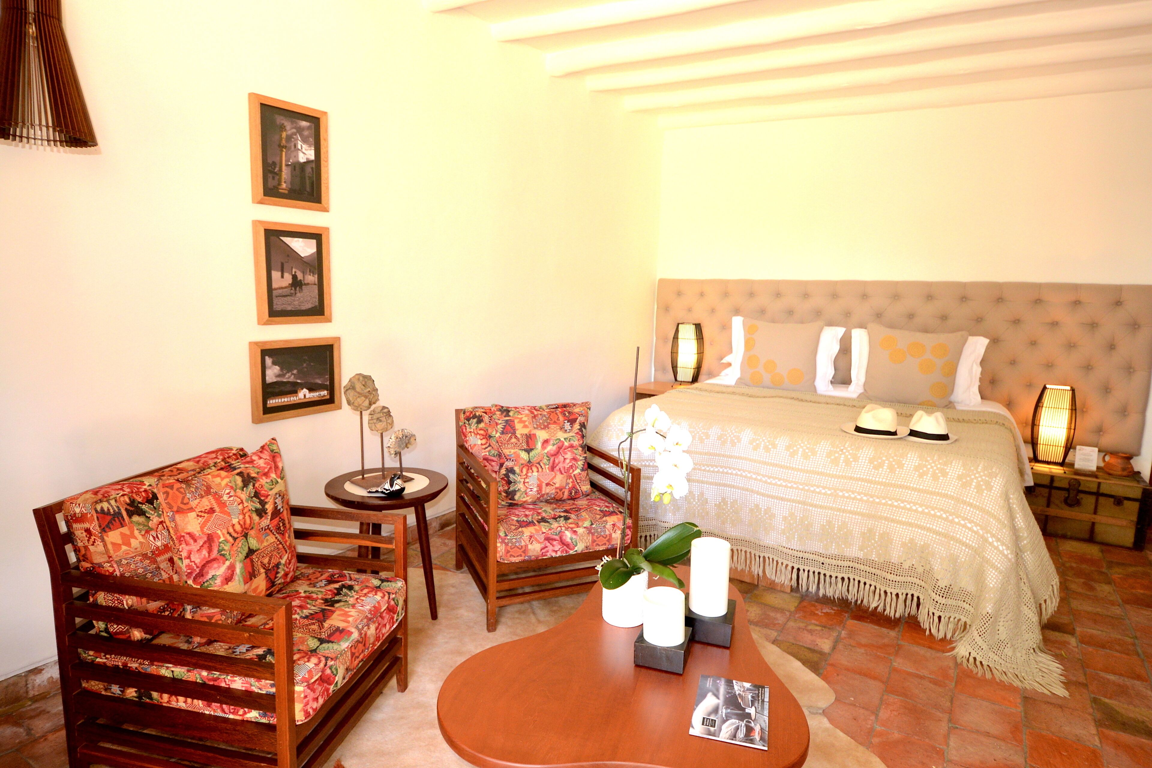 A room with a bed, two chairs, a small table, and a decorative vase.