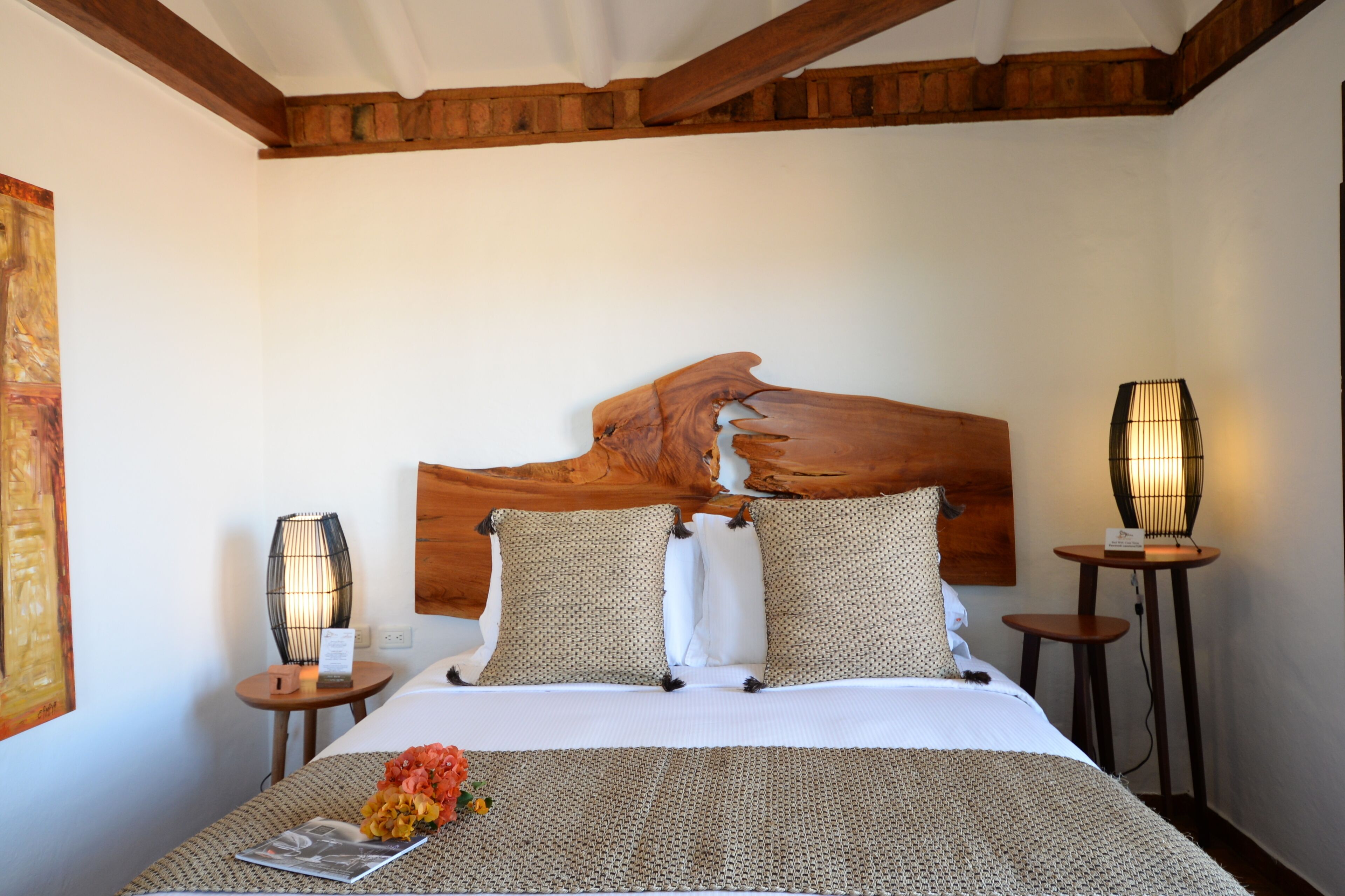 A neatly made bed with a wooden headboard, two bedside tables with lamps, and a wall-mounted artwork.
