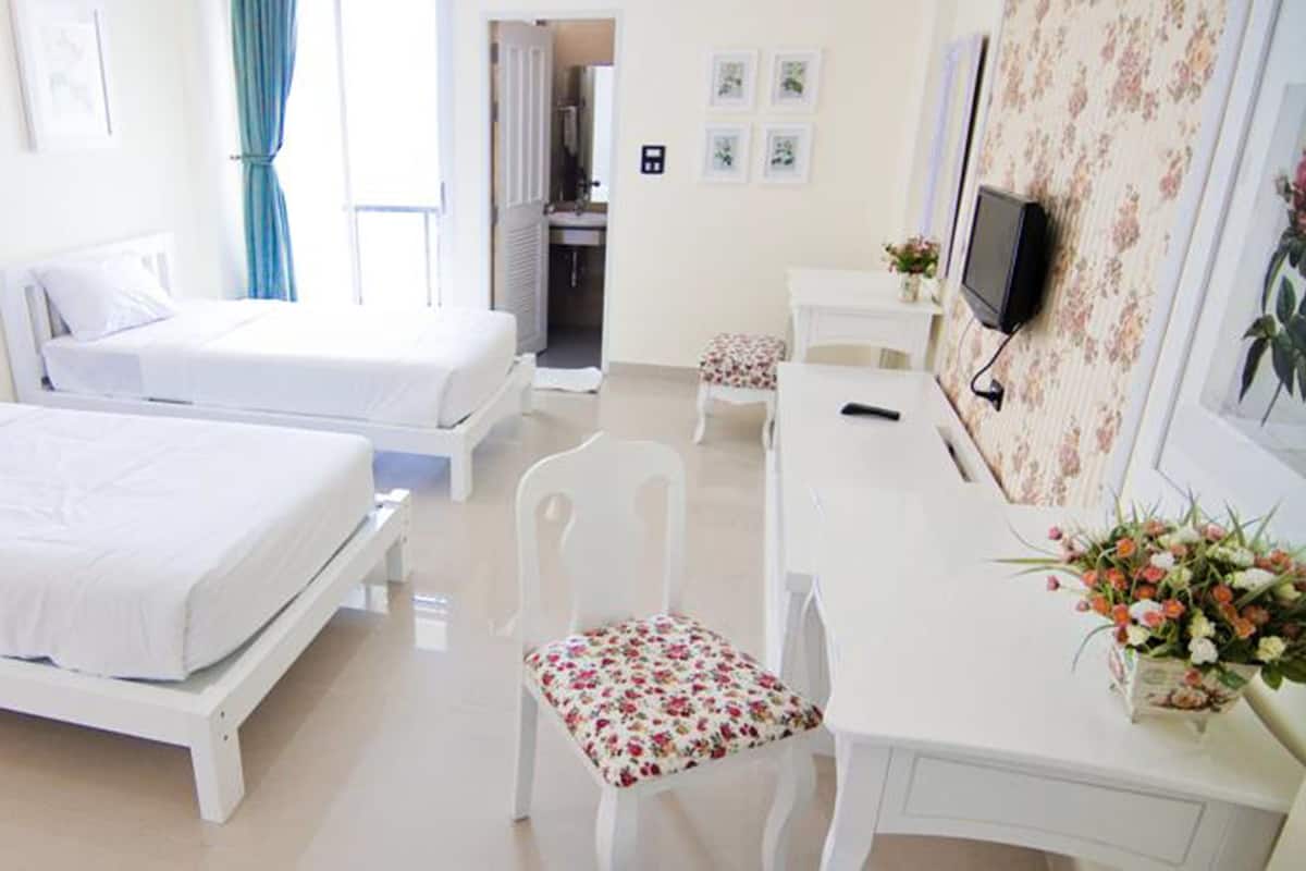 Hotelkamer met twee bedden, een bureau, een stoel, een televisie en een badkamer zichtbaar door een open deur.