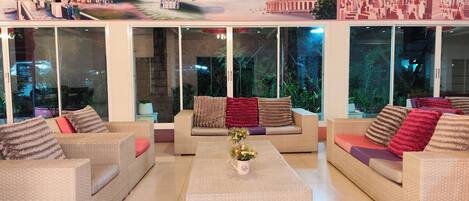 A spacious living area with wicker furniture, a coffee table, and a mural of famous landmarks.