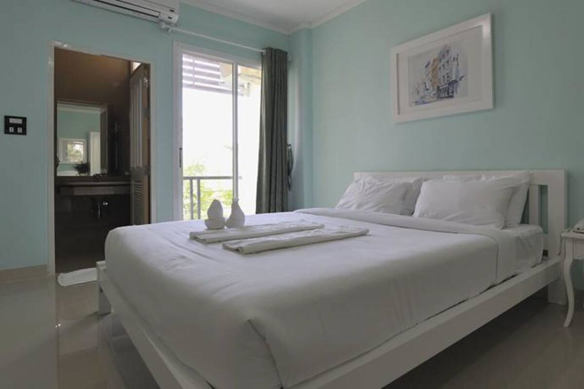 Een hotelkamer met een bed, een nachtkastje met een lamp en een schilderij aan de muur.