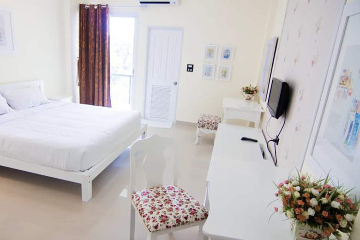 Een schone, goed verlichte hotelkamer met een bed, een bureau met een computer, een stoel en een televisie.
