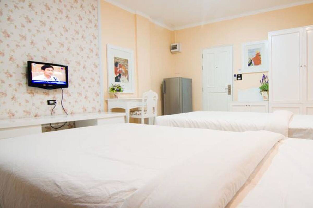 Een hotelkamer met twee bedden, een televisie, een bureau en een kledingkast.
