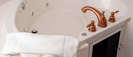 A white bathtub with a single faucet and a small window.