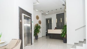 Un área de recepción moderna con mostrador, zona de estar y escalera.