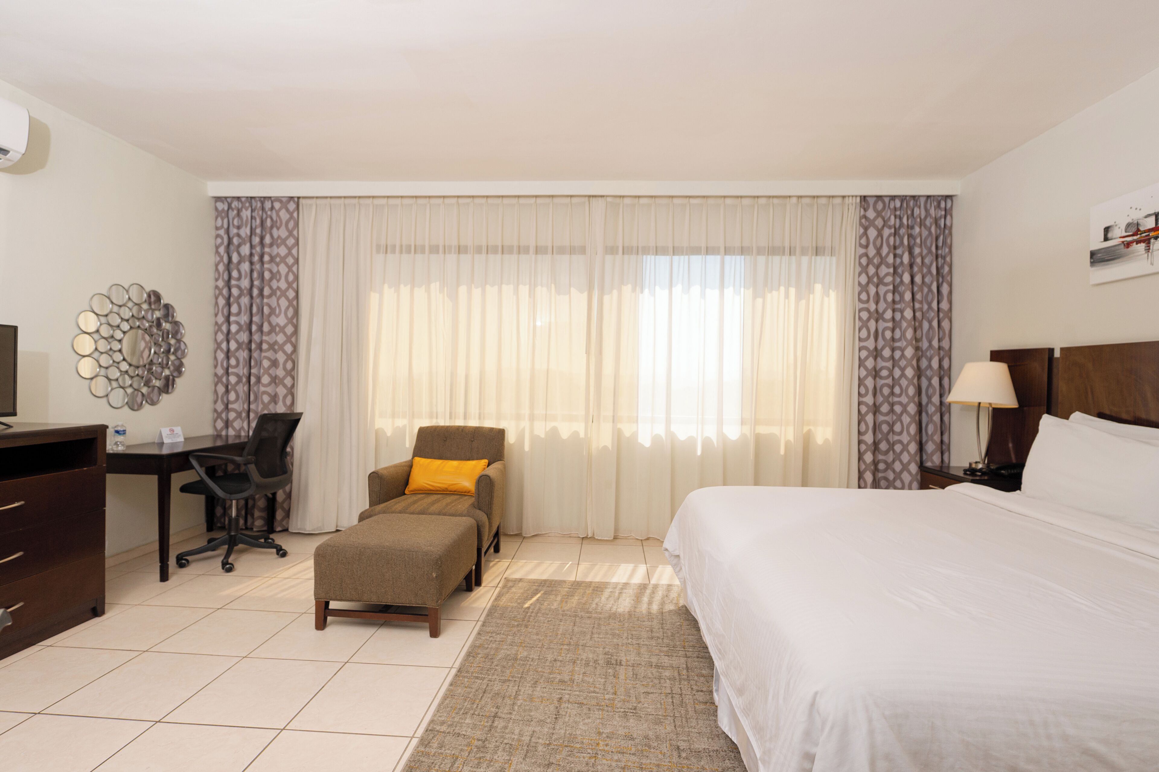 Una habitación de hotel con cama, escritorio, silla y televisión.