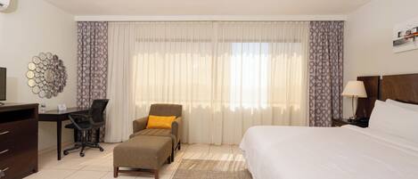 Una habitación de hotel con cama, escritorio, silla y televisión.
