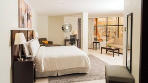 Habitación de hotel moderna con una cama grande, un escritorio, una silla, un sofá y vistas a la ciudad.