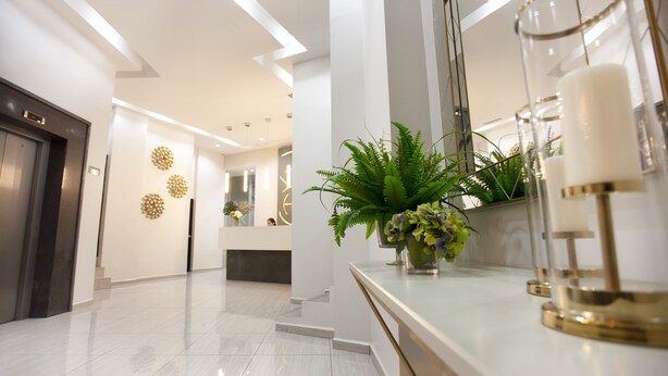 Un moderno vestíbulo de hotel con un mostrador de recepción, un espejo grande y una escalera que conduce a un piso superior.