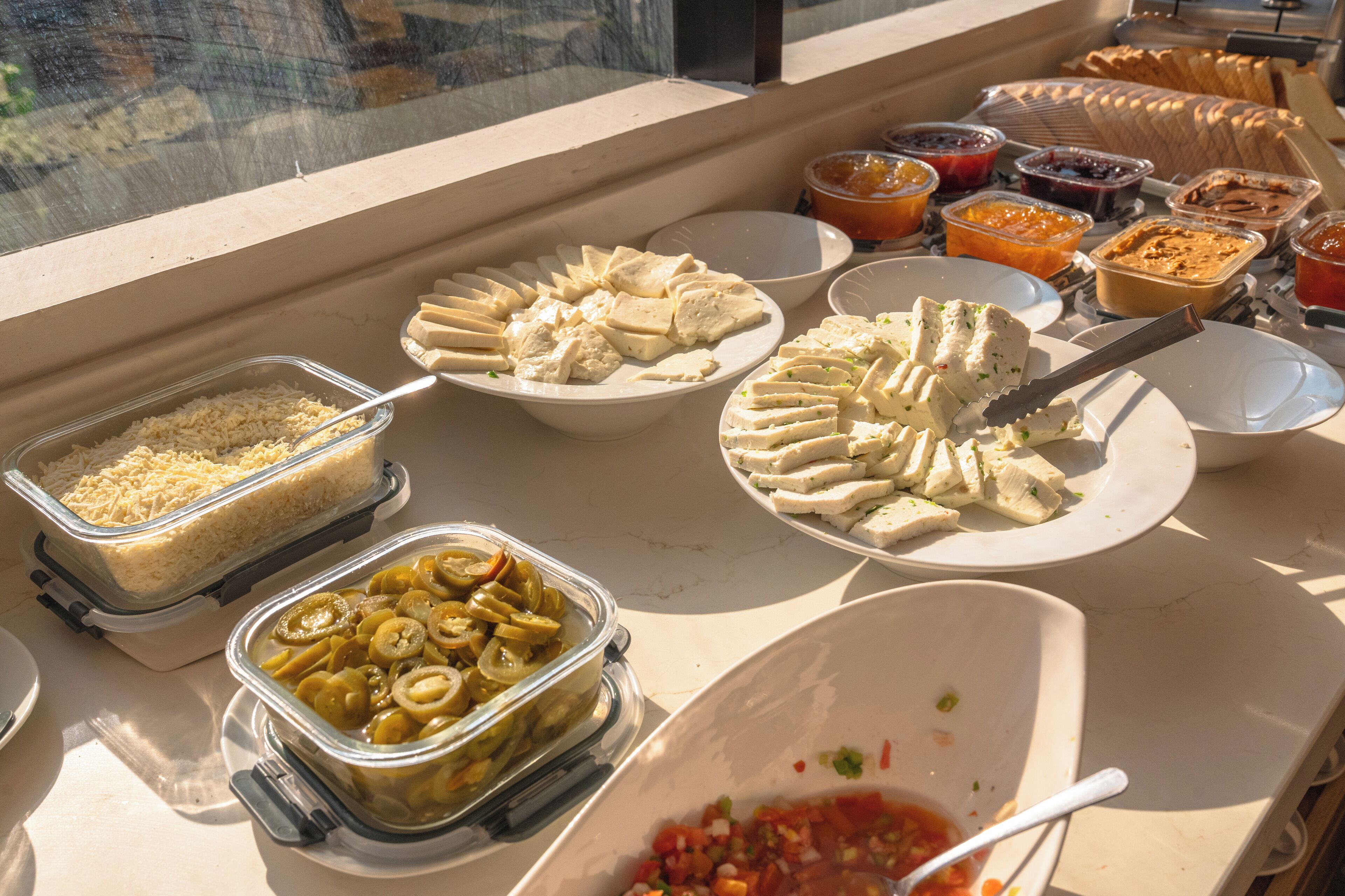 A buffet table with various food items including cheese, fruits, and condiments.
