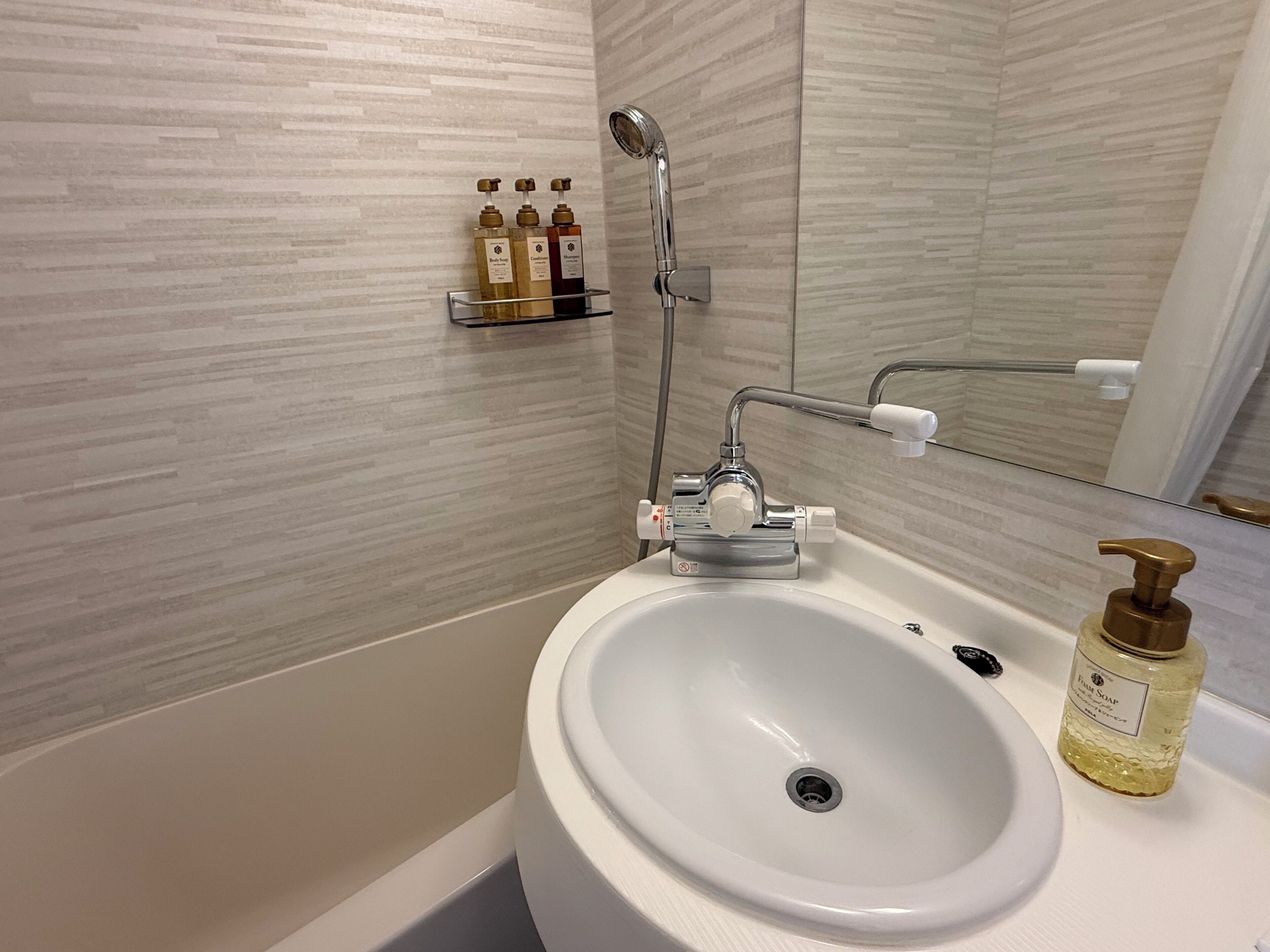 Ein Badezimmer mit einem weißen Waschbecken, einer Duschbrause und einem Spiegel.
