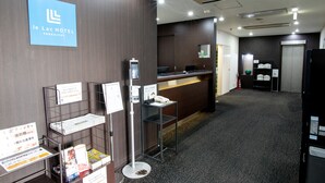 Un espace d’accueil avec un panneau bleu, un comptoir d’accueil, un téléphone et des brochures d’information.