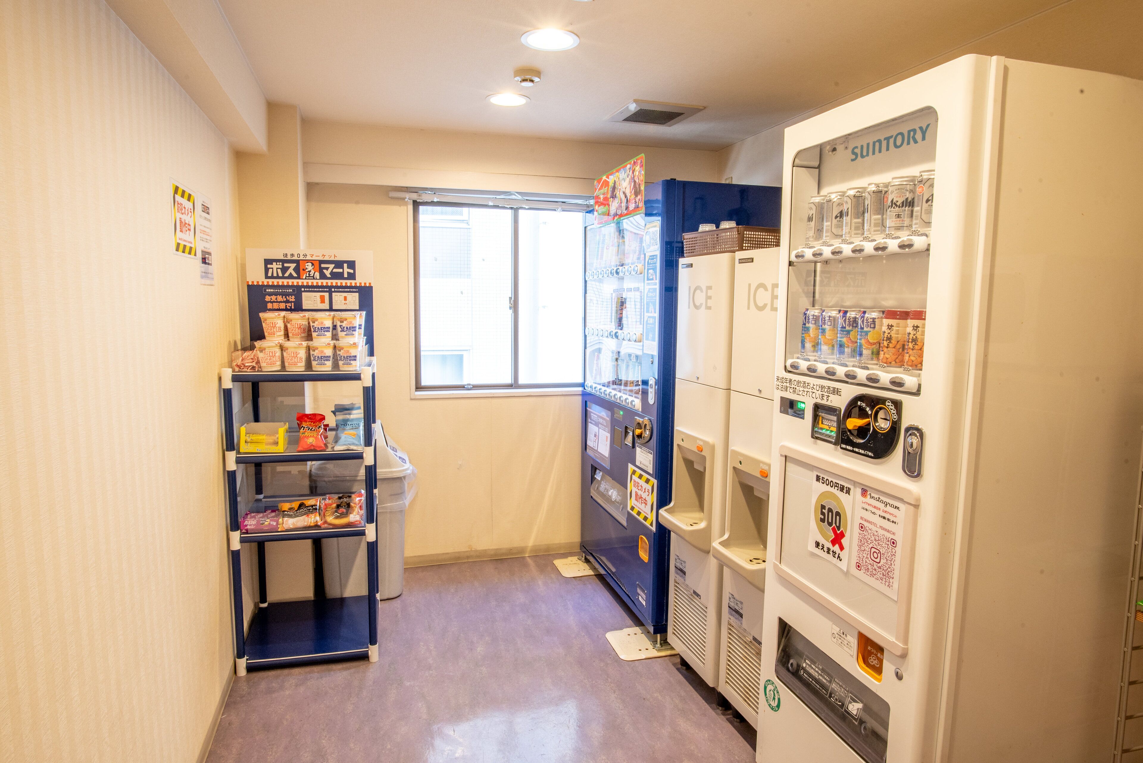 A narrow hallway with vending machines, a small shelf with snacks, and a window.