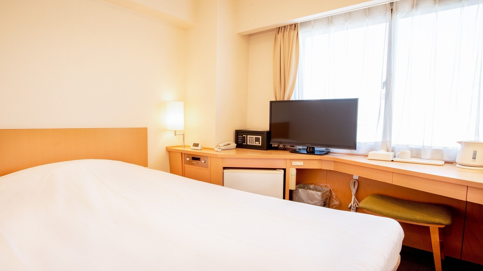 Une chambre d’hôtel équipée d’un lit, d’un bureau avec une télévision, d’une lampe et d’une machine à café.