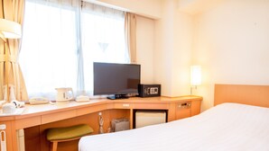 Une chambre d’hôtel équipée d’un lit, d’un bureau avec une télévision, d’un four à micro-ondes et d’une petite poubelle.