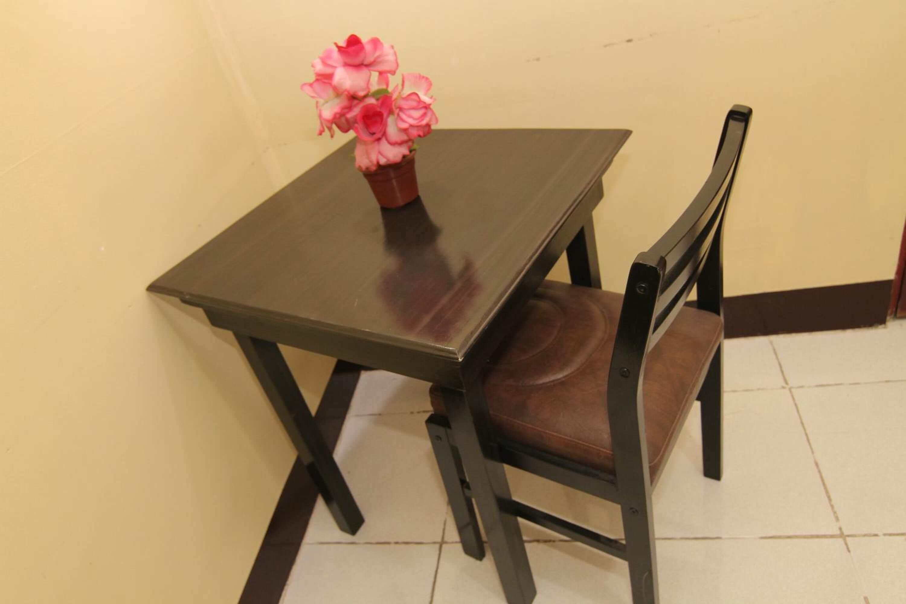 A small dining table with a potted plant and a single chair.