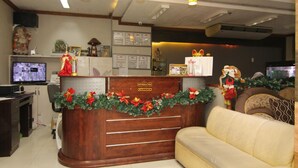 A reception area with a wooden desk, a sofa, and holiday decorations. - Honey Hunt House (Cebu City)