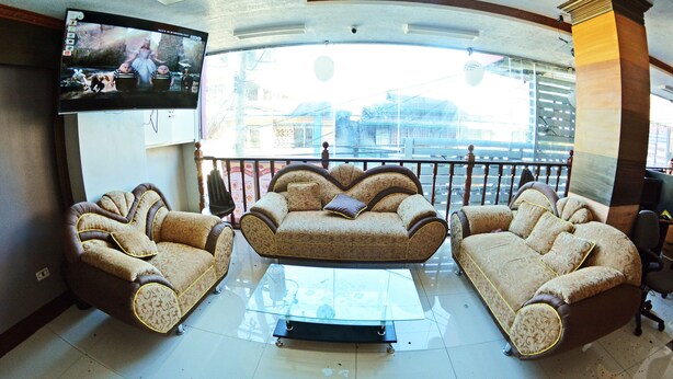 A living room with a sofa set, a glass coffee table, and a television mounted on the wall. - Honey Hunt House (Cebu City)