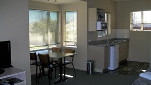 Una cocina compacta con comedor, un refrigerador pequeño y un microondas.