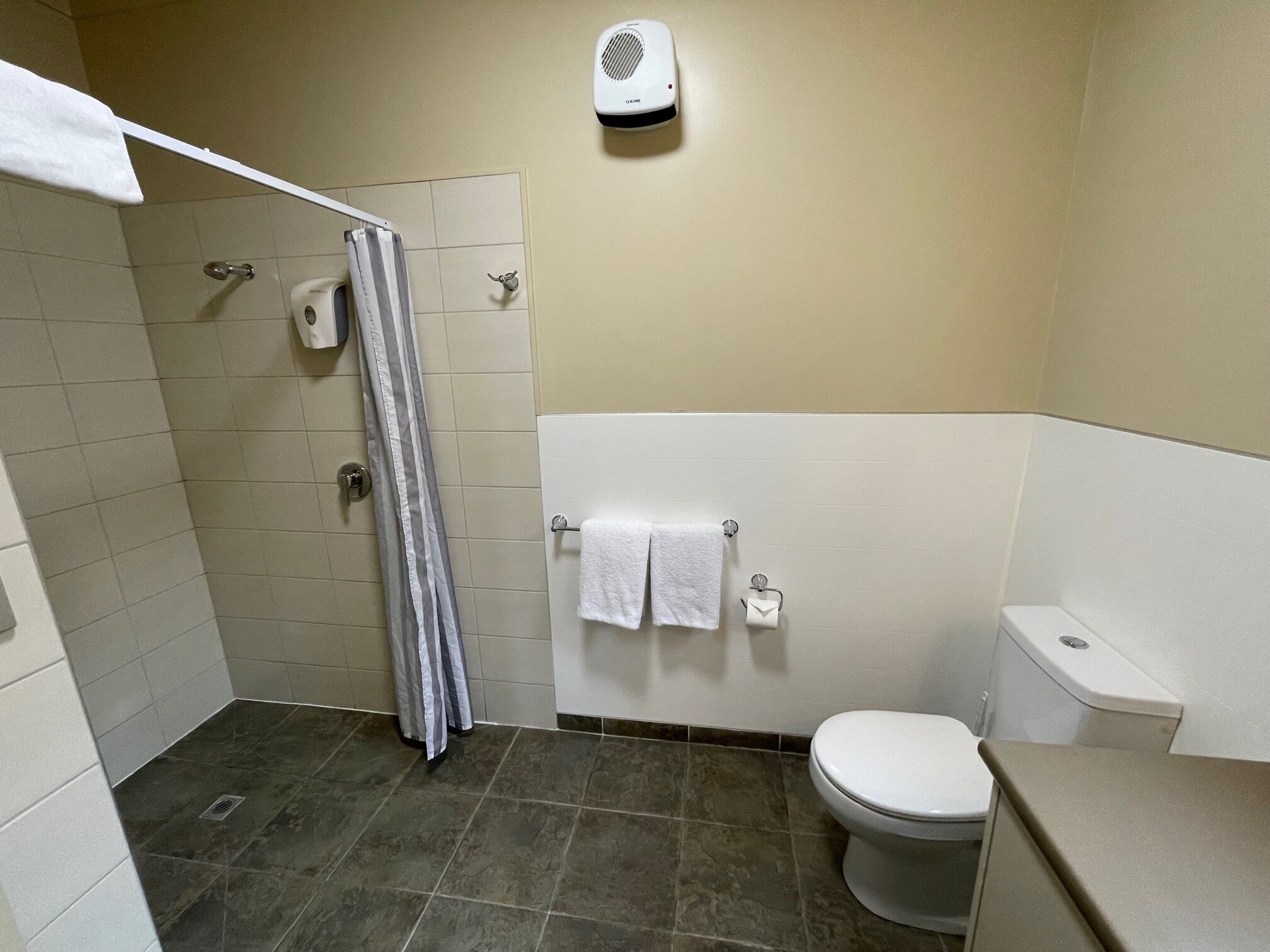 Un baño con ducha, inodoro y barra para toallas.