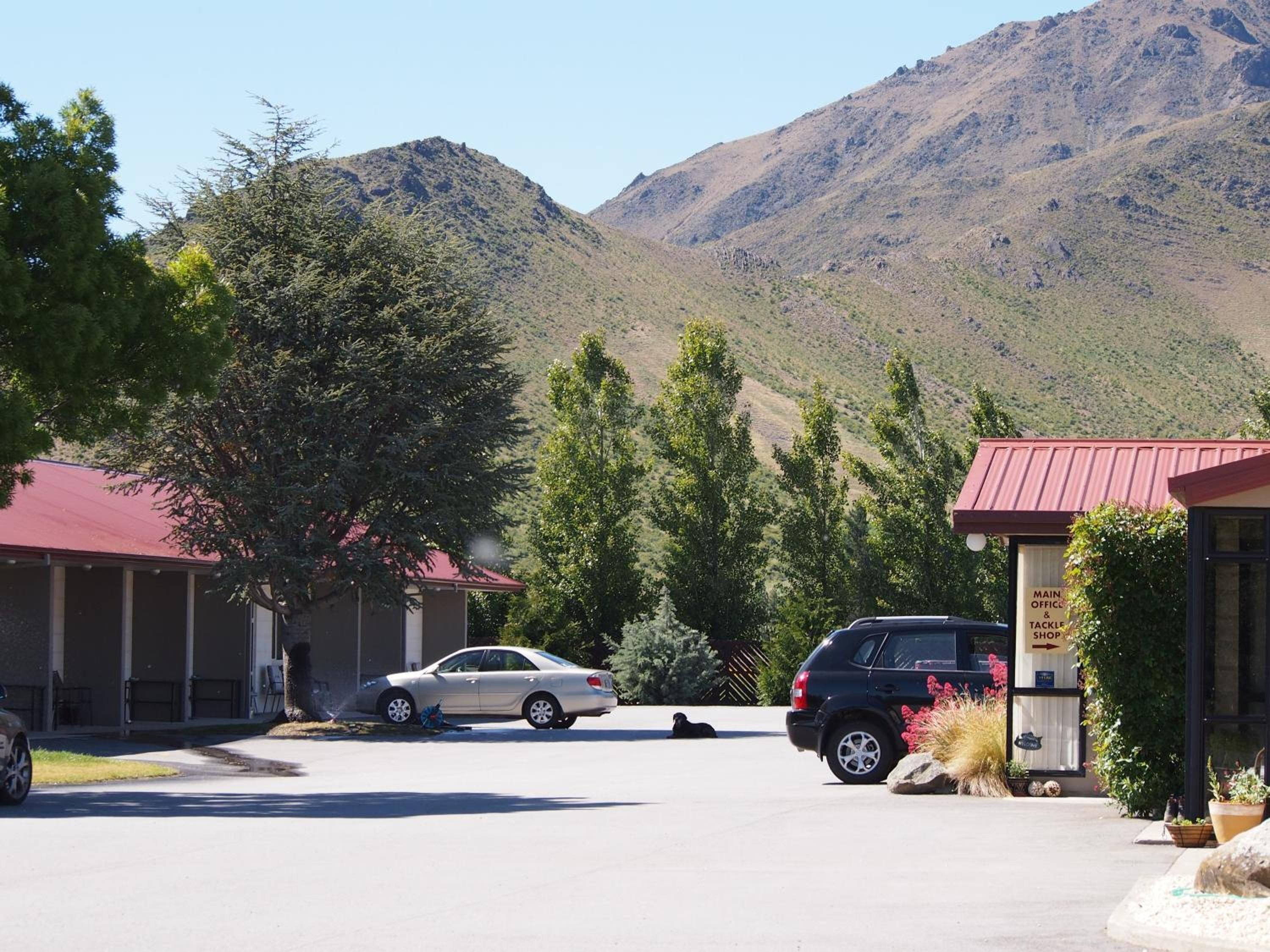 A building with a red roof, a parking lot, and a mountainous backdrop.