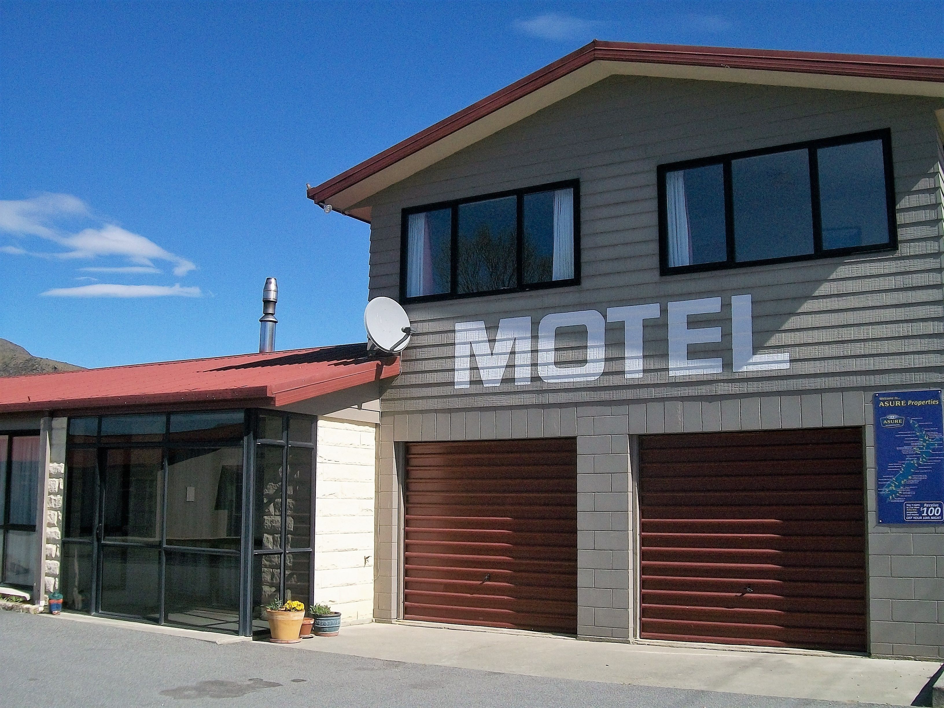 Een motel met een groot bord, een schotelantenne en een gesloten garage.