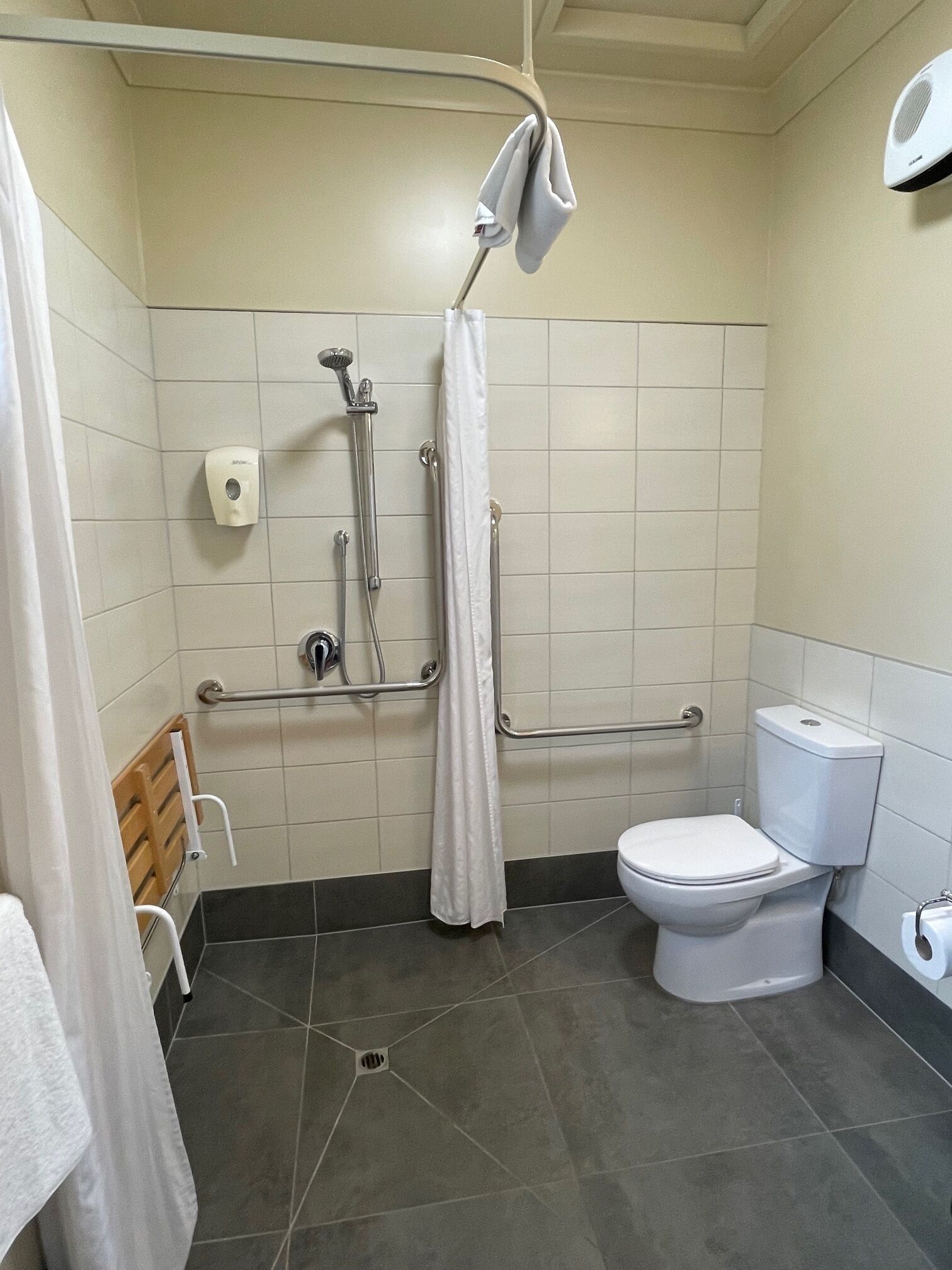 A bathroom with a shower, toilet, and hand dryer.
