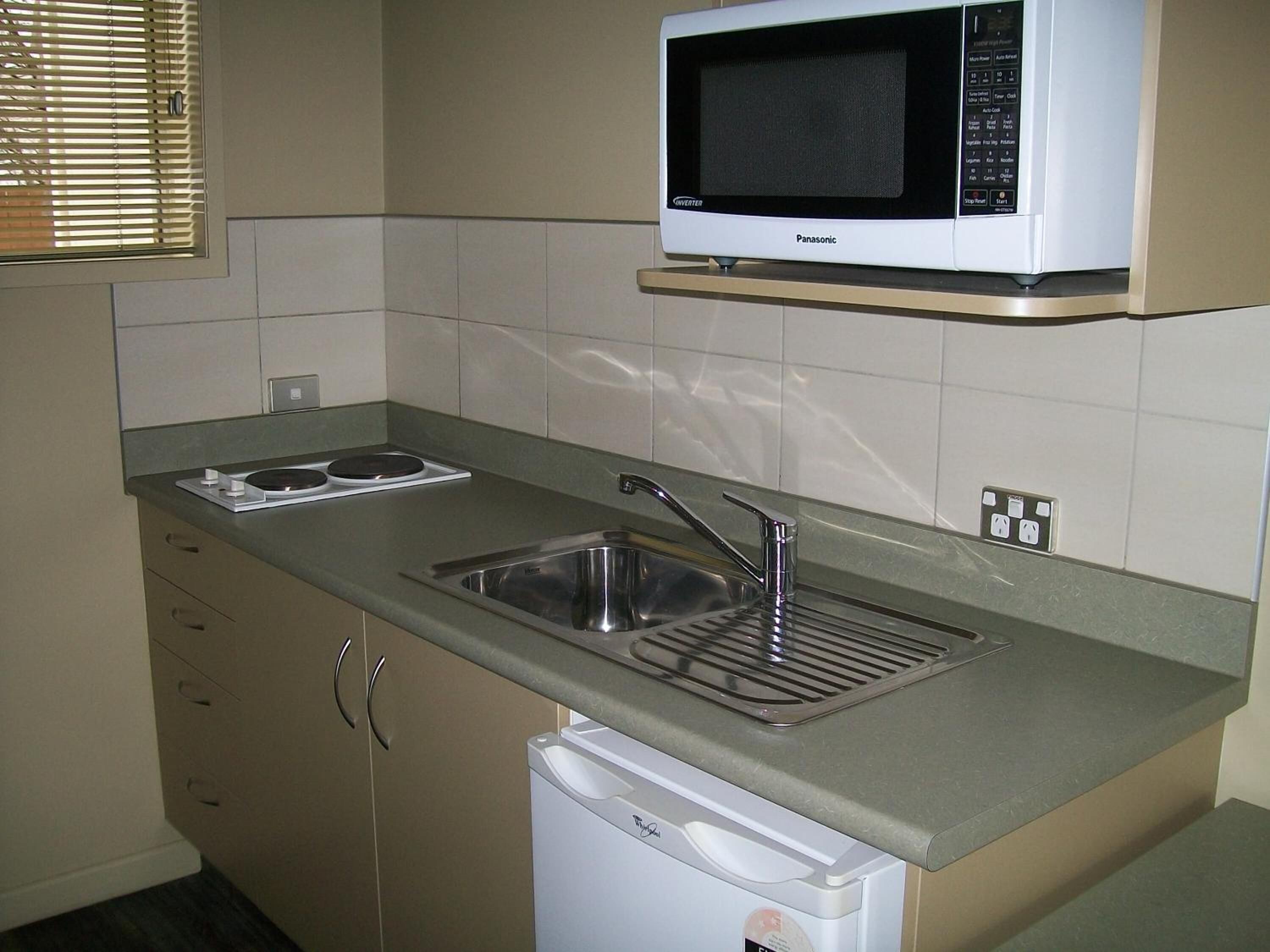 A compact kitchen with a microwave, sink, and dishwasher.
