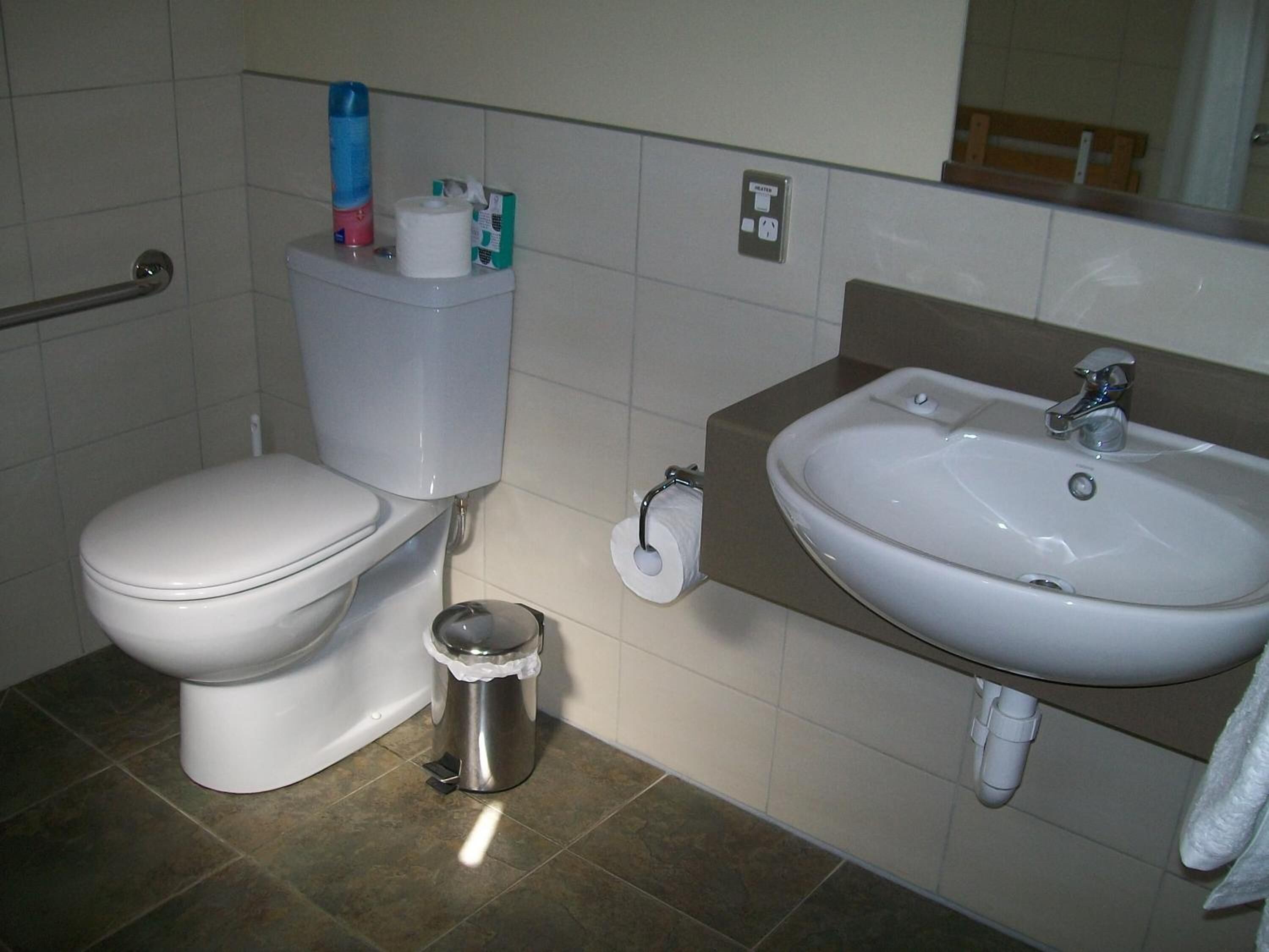 A bathroom with a toilet, a sink, and a trash can.