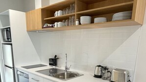 Una cocina moderna con armarios blancos, lavavajillas integrado, un fregadero y un tostador.