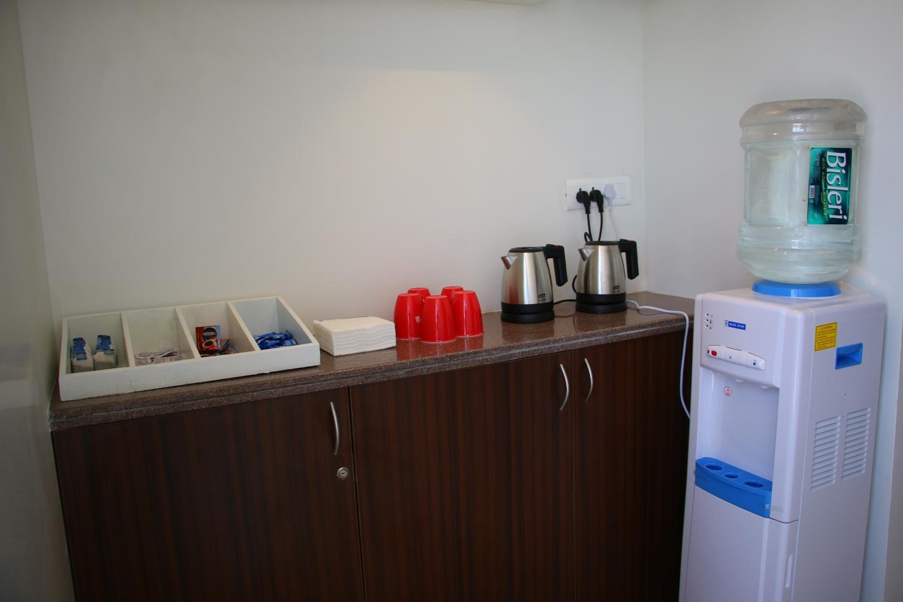 Angolo cottura con dispenser di acqua, macchina del caffè e bollitore sul piano di lavoro.