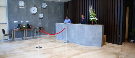 A reception area with a reception desk, multiple clocks on the wall, and a red rope barrier.