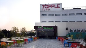 Un hotel con restaurante llamado 'Tulip Restaurant' y terraza al aire libre con sillas y mesas de colores.