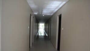Um corredor comprido e estreito com portas em ambos os lados, que leva a uma área luminosa no final.