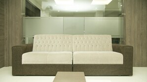 Uma sala de estar moderna com um sofá estofado, uma mesa de centro de madeira e uma divisória de parede de vidro.